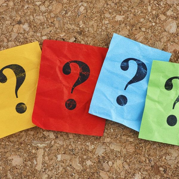 Colorful paper notes with question marks on a cork board