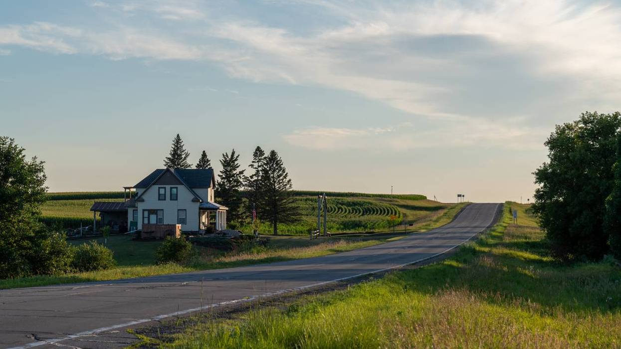 country road lined with fields and a white farmhouse