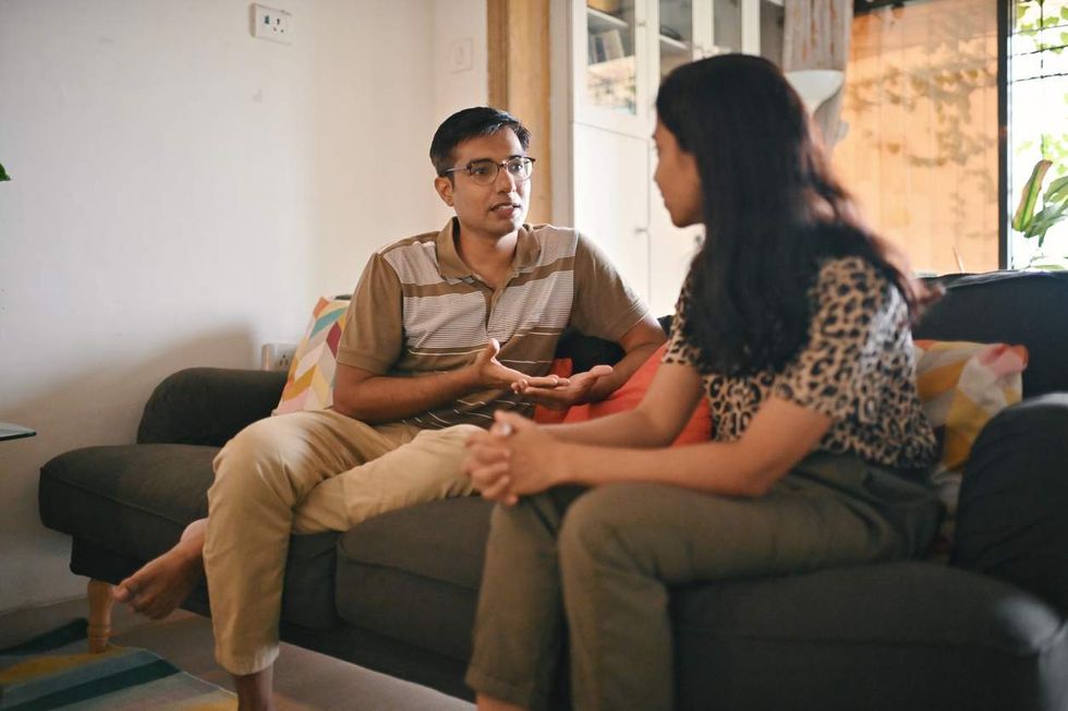 couple having a serious discussion sitting on a sofa in living room