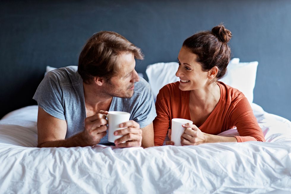 couple lying on their bed drinking coffee