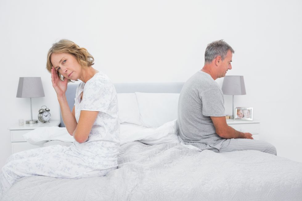 couple sitting on different sides of bed