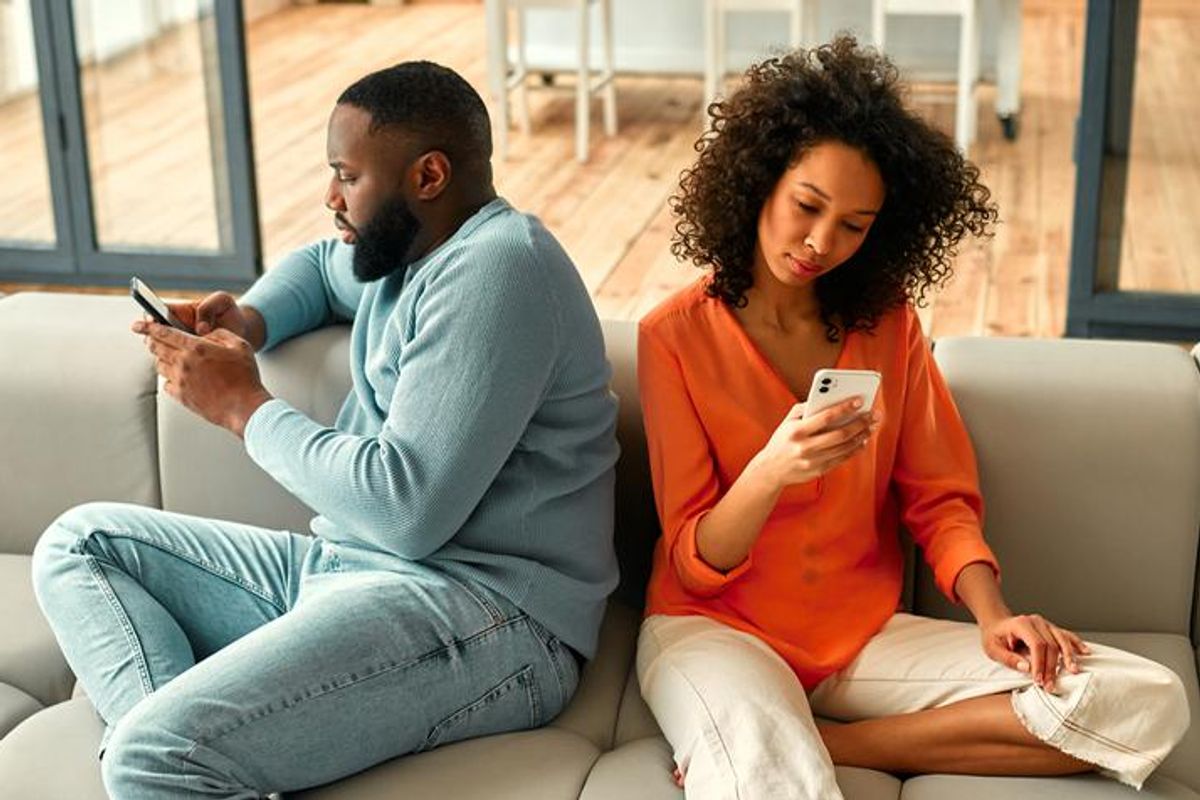 couple sitting on the couch looking at their own phones