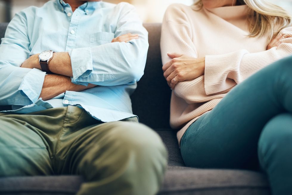 couple sitting on the sofa with their arms folded after an argument