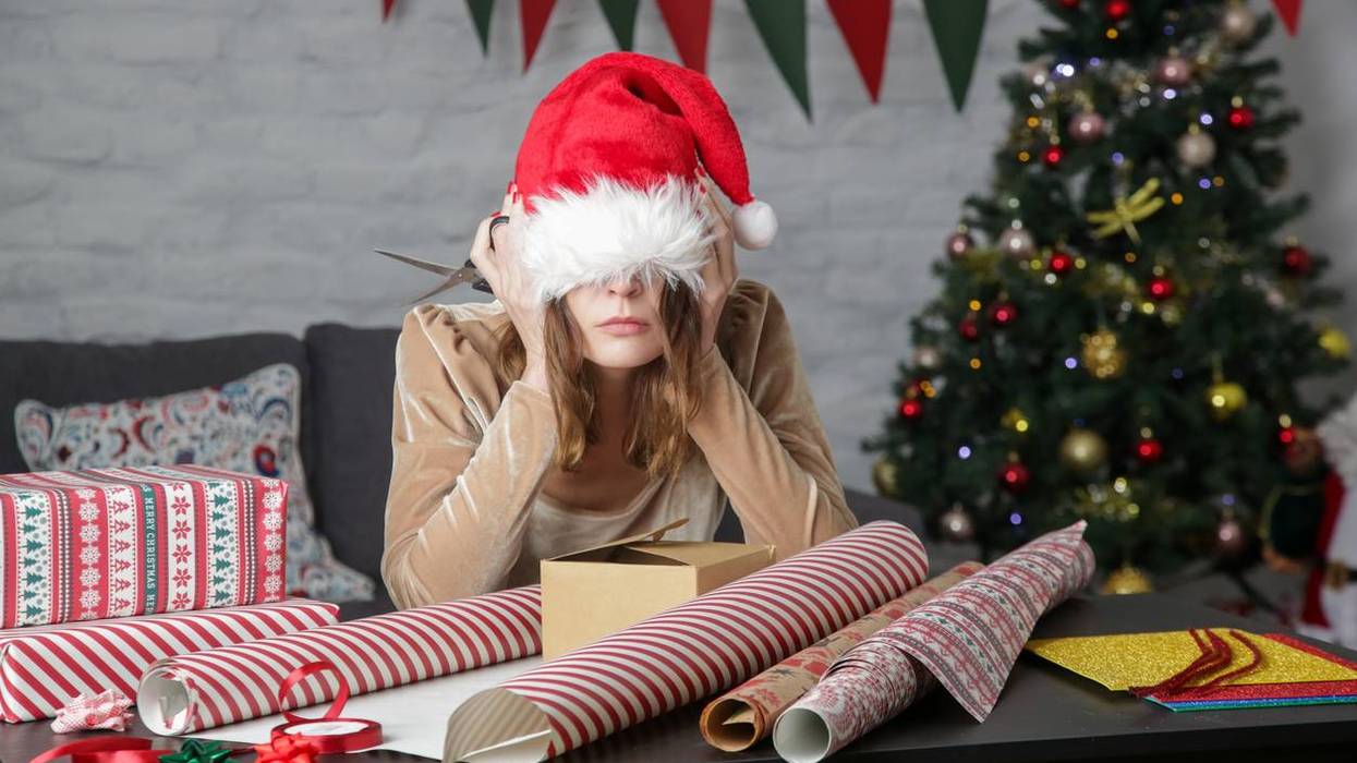 Depressed frustrated woman wrapping Christmas gift boxes