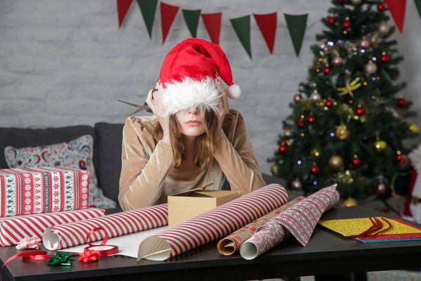 Depressed frustrated woman wrapping Christmas gift boxes