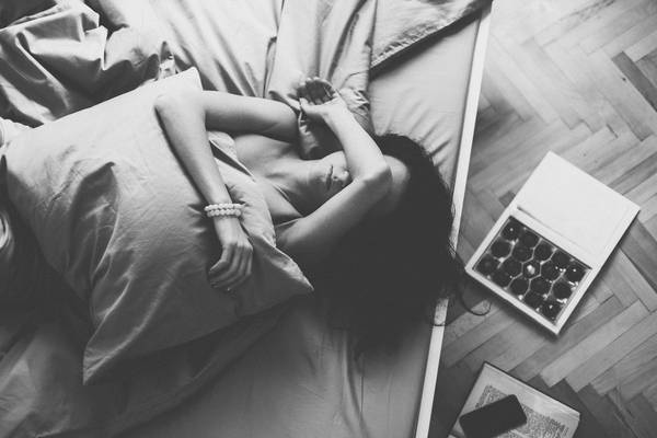 Depressed woman in bed with hand on forehead