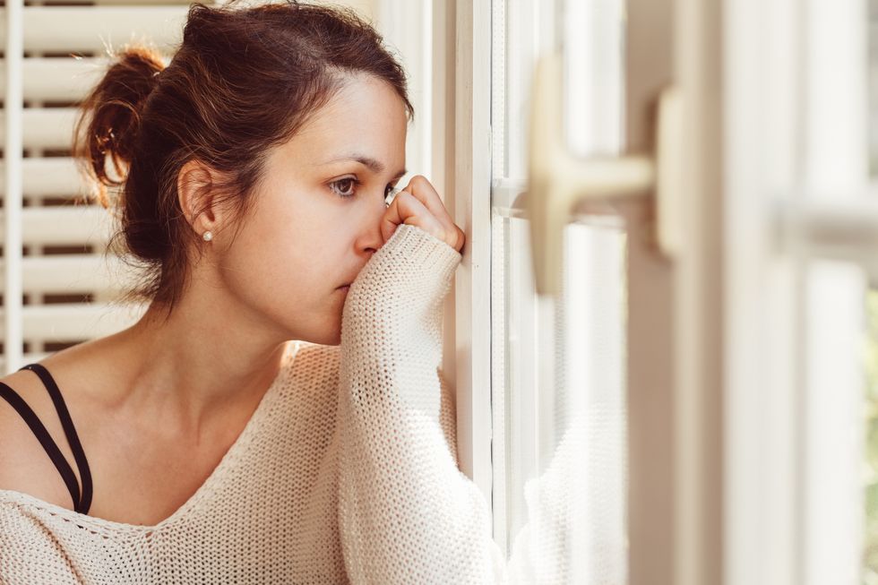 Depressed woman looking through window