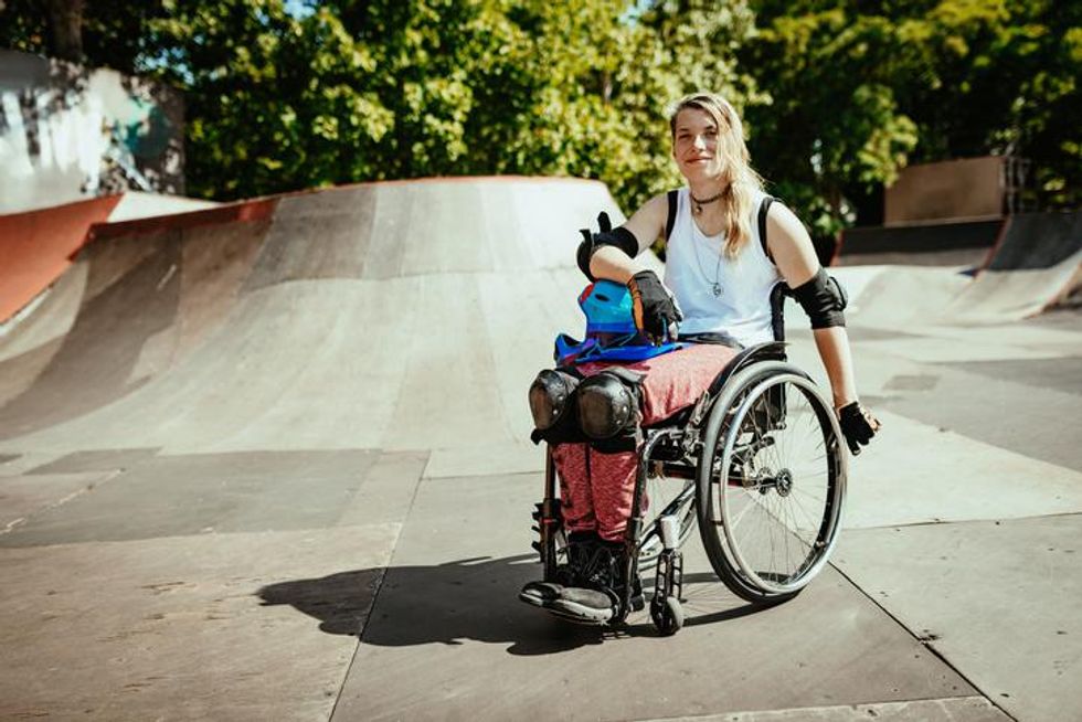 Disabled woman in wheelchair doing stunts in skate park