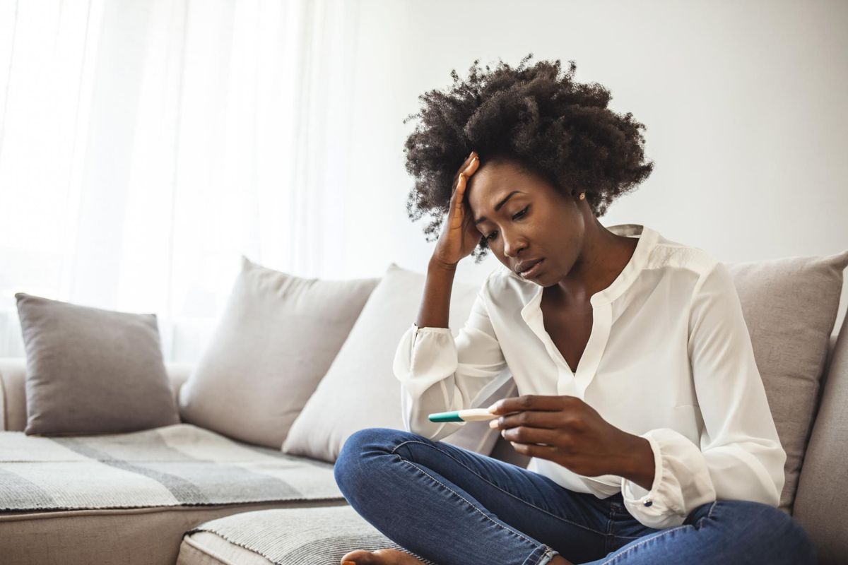 Disappointed african-american woman getting unexpected result from pregnancy test