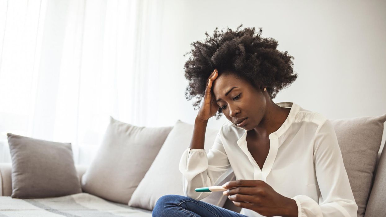 Disappointed african-american woman getting unexpected result from pregnancy test