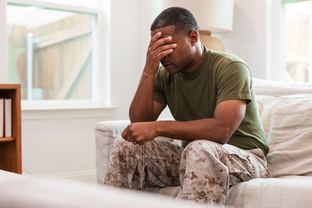 Distraught male soldier sits alone in living room