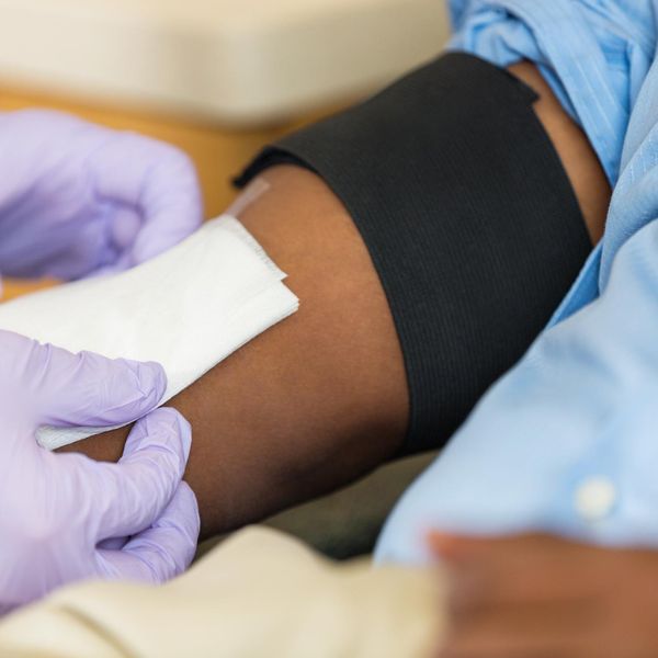 Doctor bandaging arm of patient who is giving blood