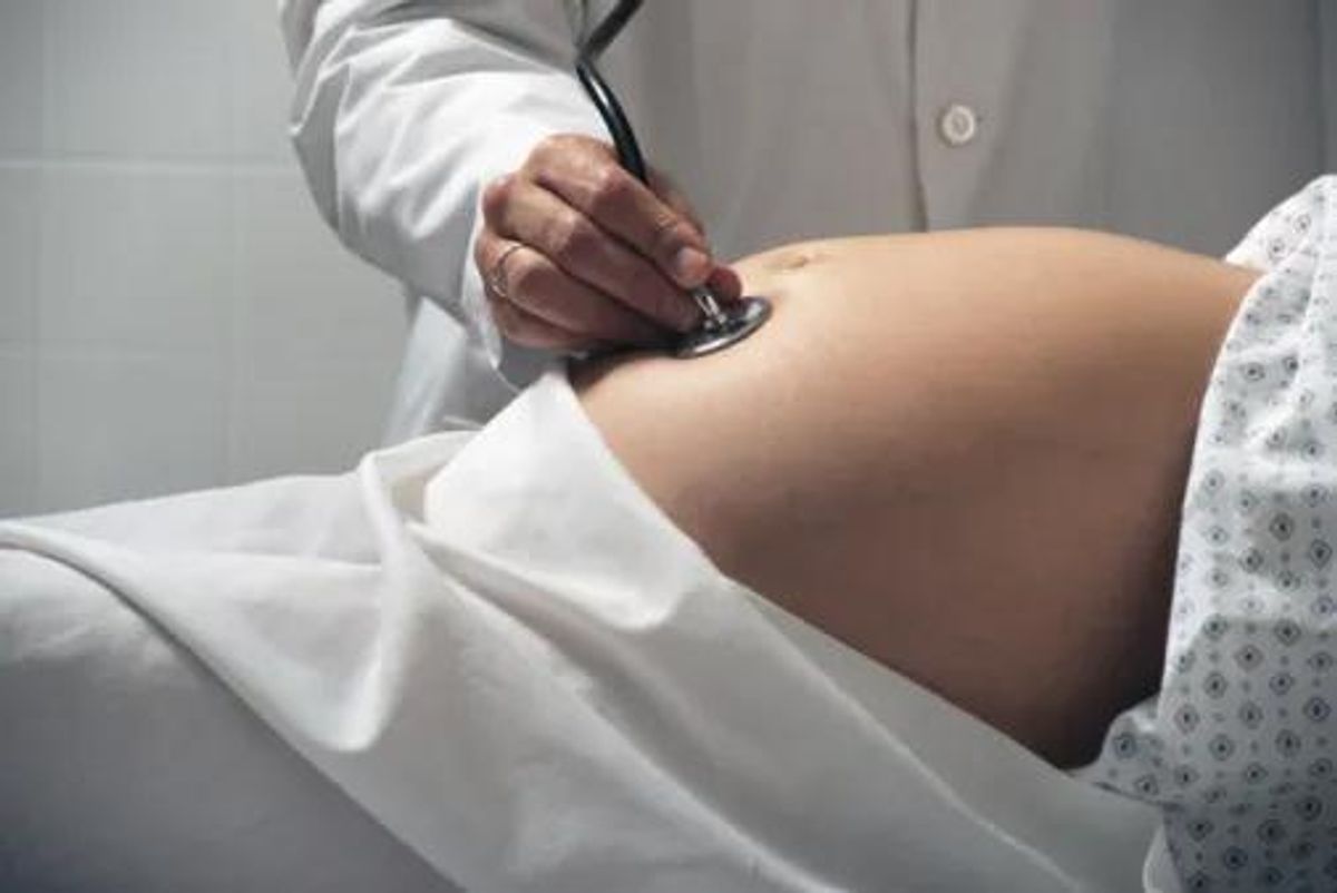 doctor listening to the belly of a pregnant woman