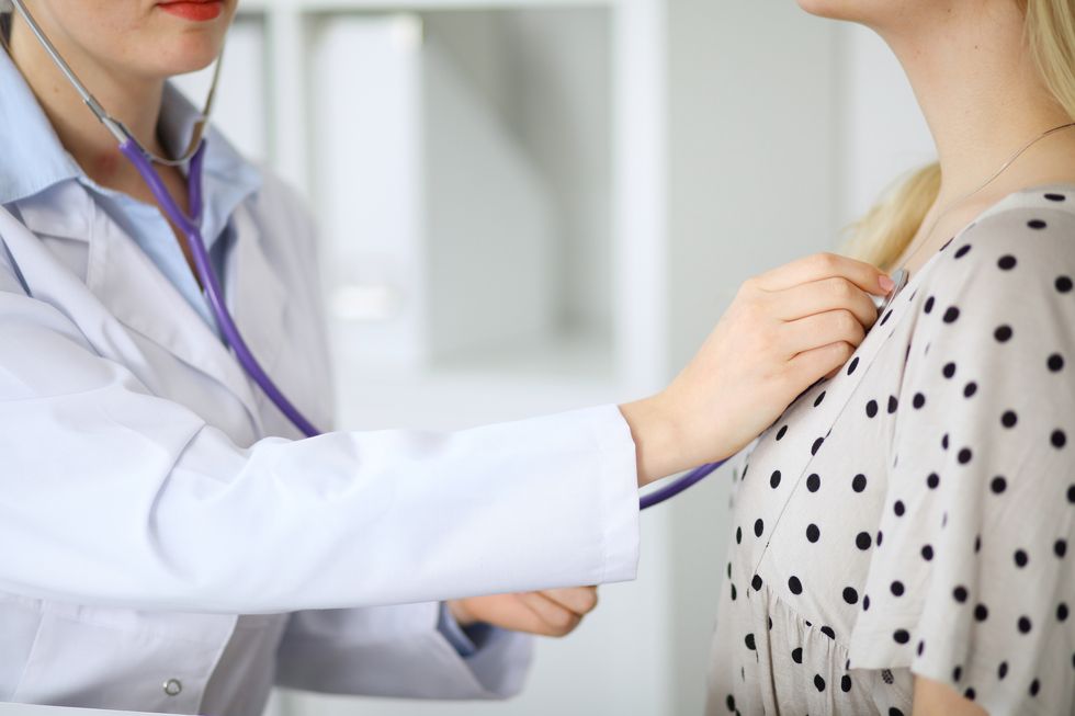 doctor listening to womans chest with a stethoscope