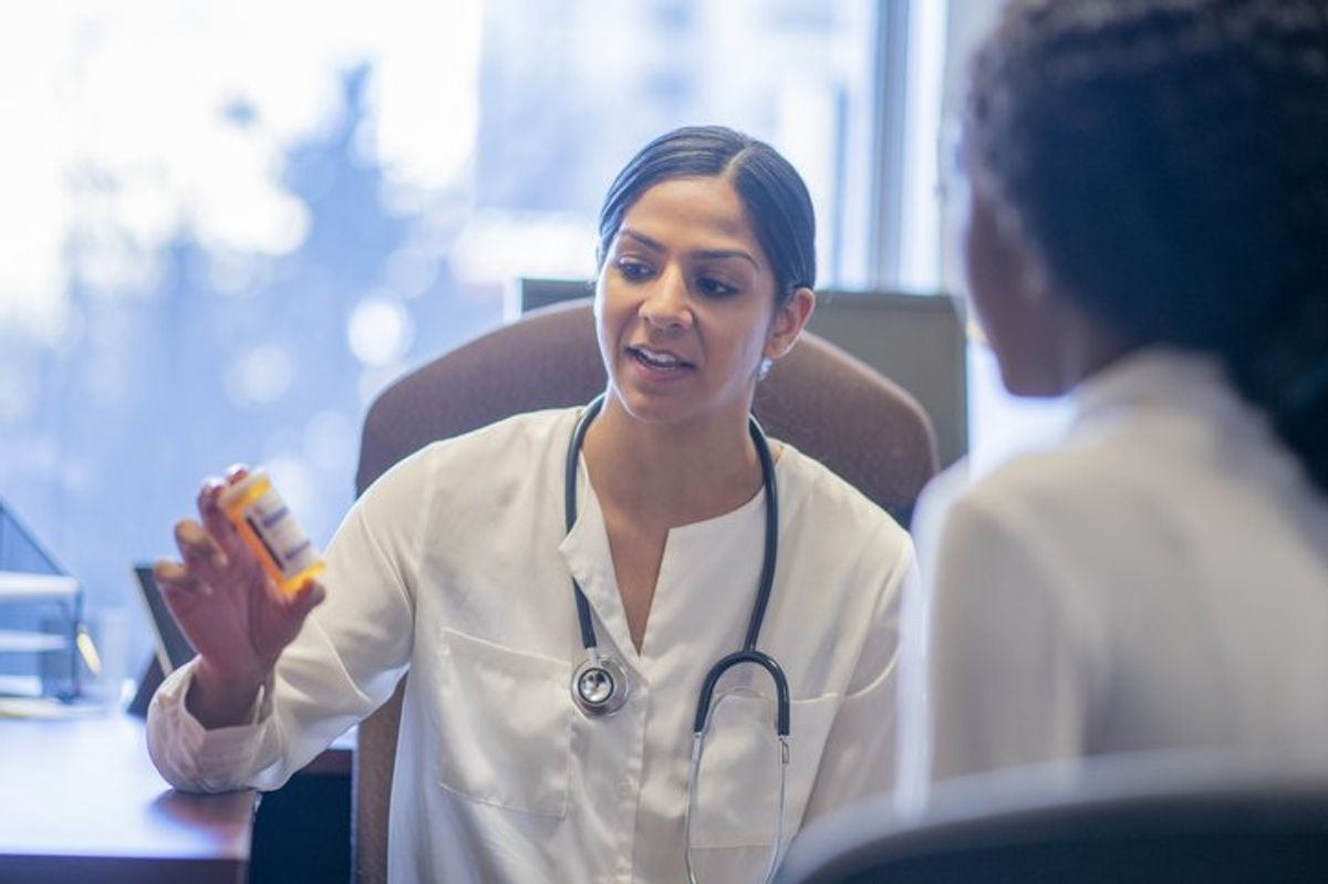 doctor talks with her African patient about her new medication