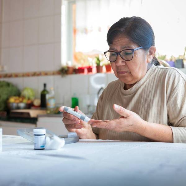 Elderly woman checking blood sugar level at home