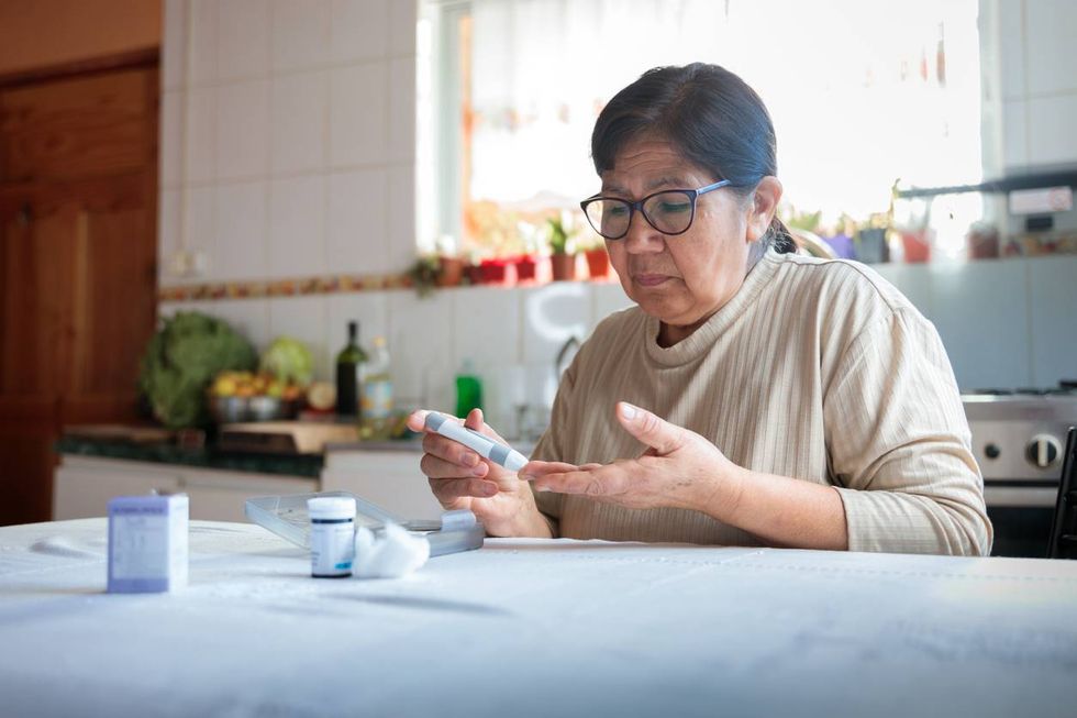 elderly woman checking blood sugar level at home