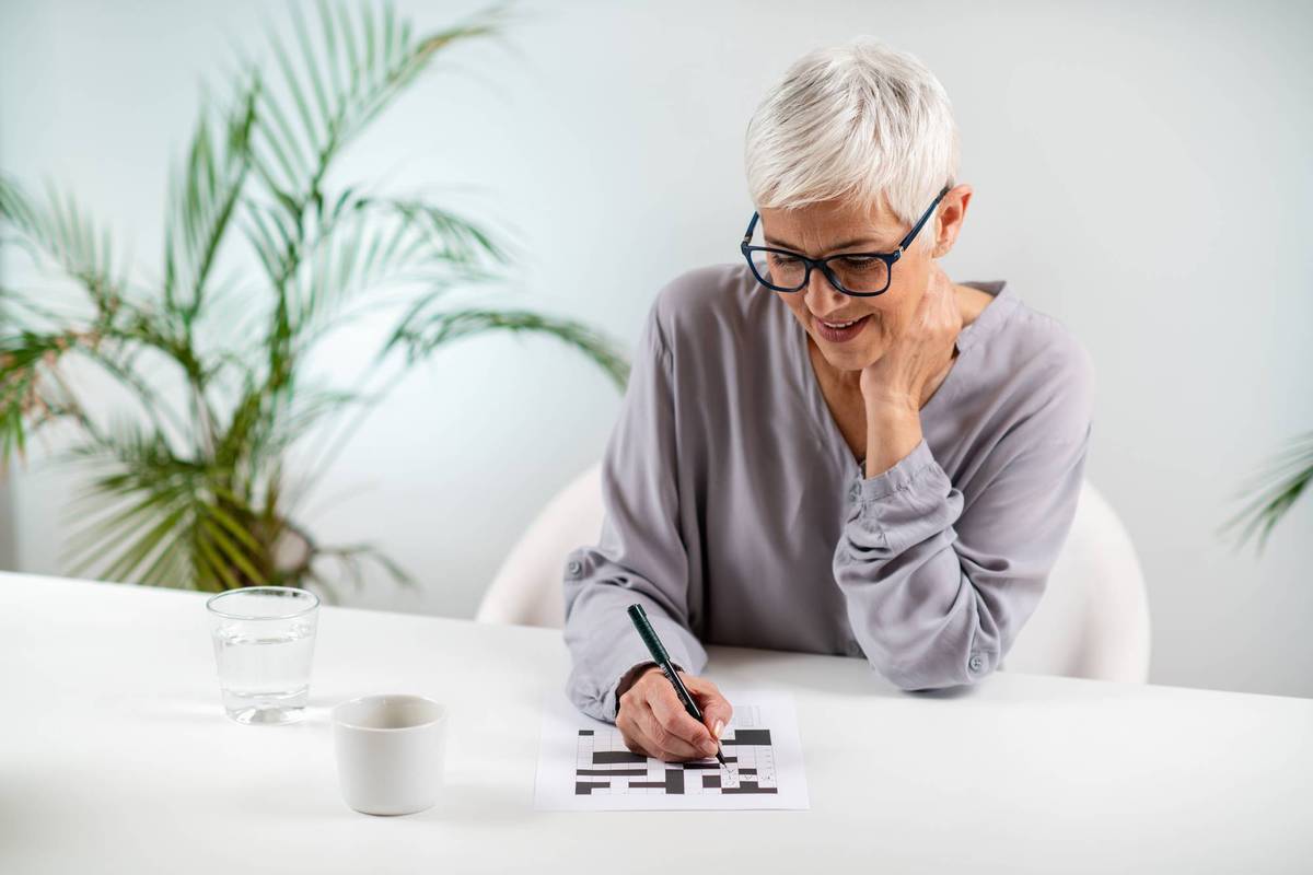 Engaging cognitive activity as a senior woman solves crossword puzzles, promoting mental stimulation and brain health