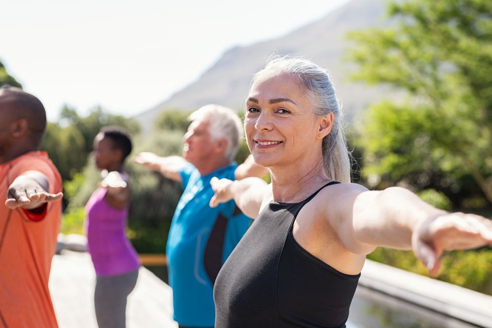 enior woman stretching arms in yoga class