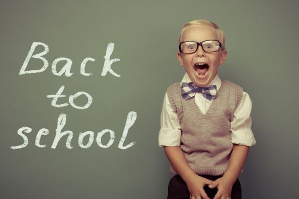 excited child next to a back to school sign
