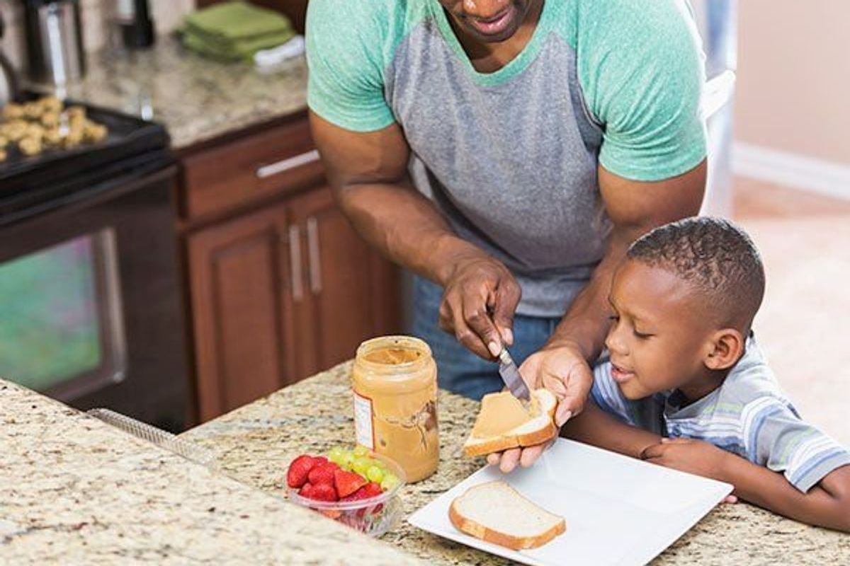 father making a peanut butter sandwich for his son