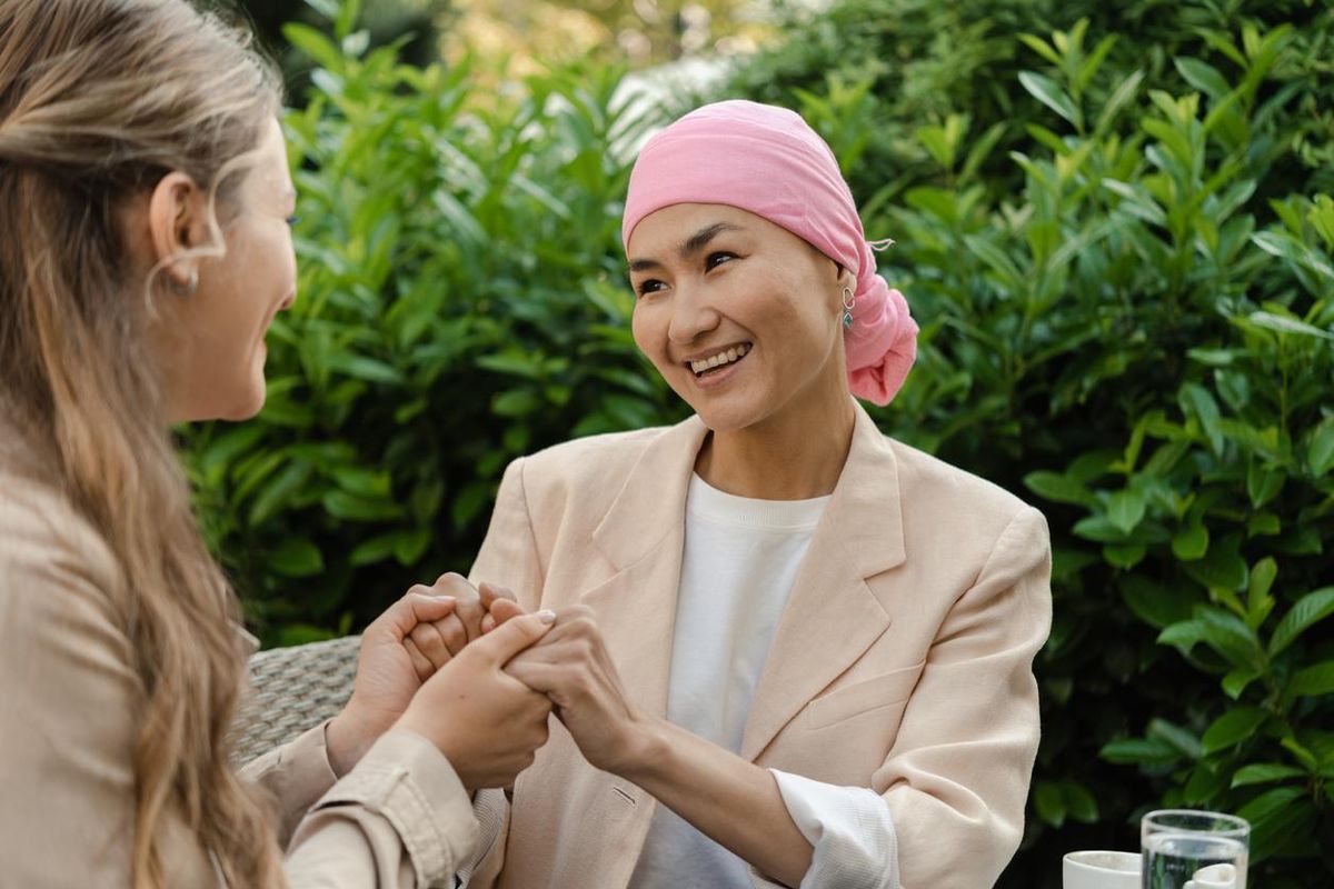 female cancer patient with a headscarf enjoying at the cafe with her best friend