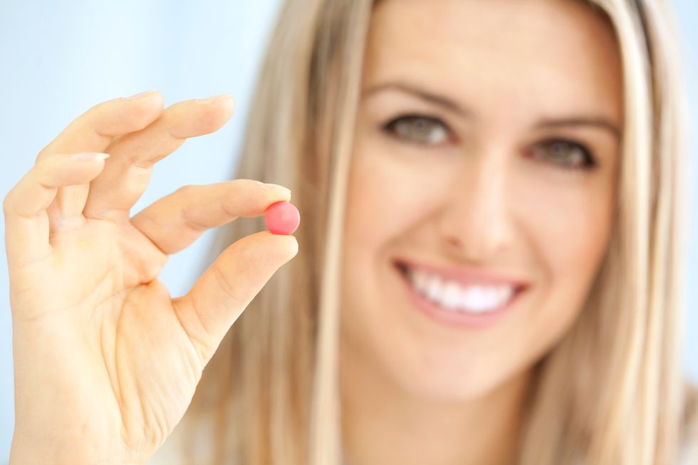 female doctor holding small pink pill