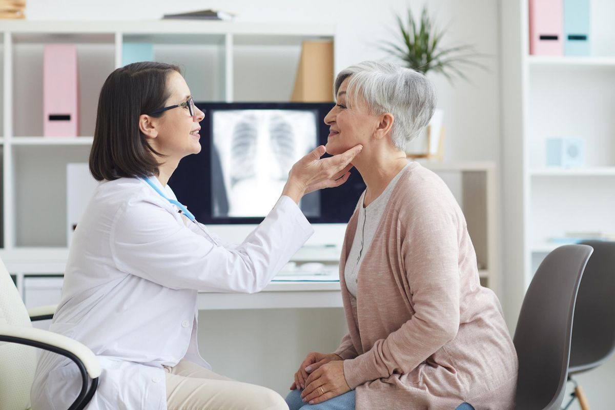 Female Doctor Palpating Neck of Senior Woman