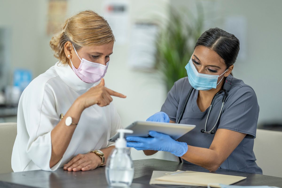 Female doctor speaking with patient wearing masks discussing a Hysterectomy