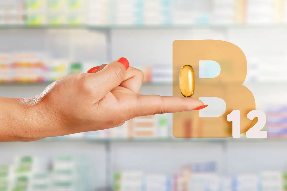 Female hand floating giant pill with Vitamin B-12 in pharmacy