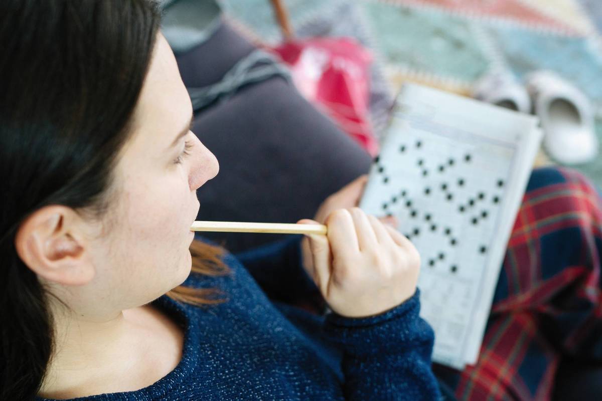 Female hand holding a pencil and solves crossword puzzle to fight cognitive decline