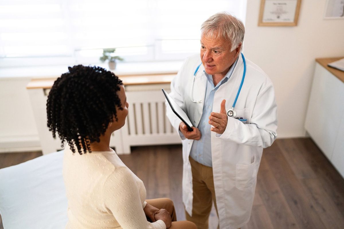 female patient of African-American ethnicity, having an annual medical check-up with a senior male Caucasian doctor