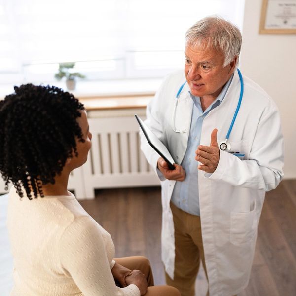 female patient of African-American ethnicity, having an annual medical check-up with a senior male Caucasian doctor