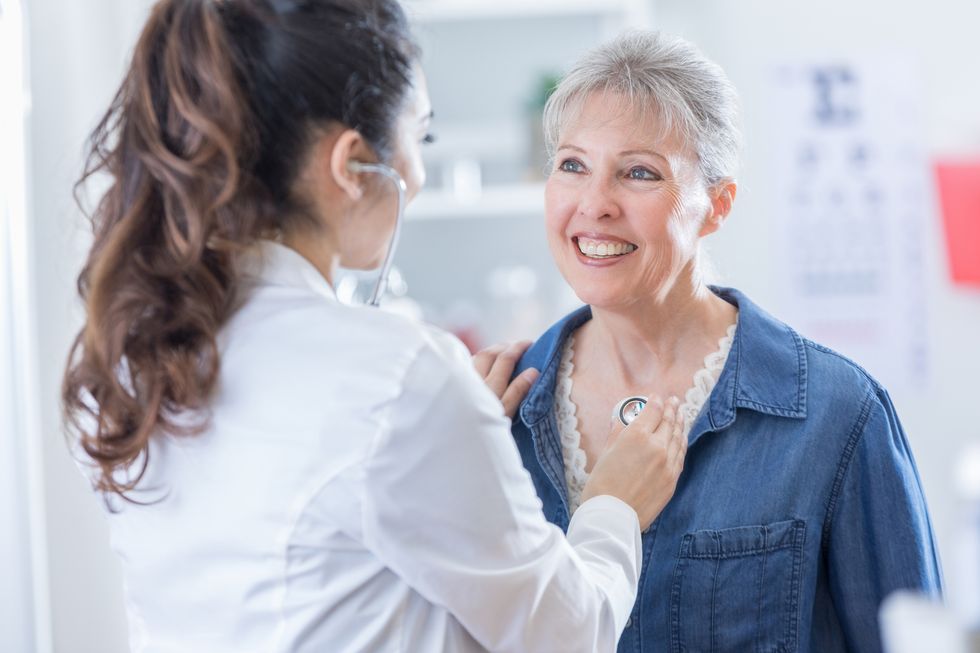 Female physician listens to senior patient's heart