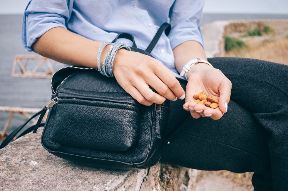 Female's hand holding a handful of almonds next to an open bag