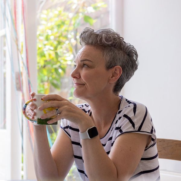 female sitting at a table in a kitchen, relaxing and having a cup of tea