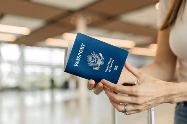 Female traveler holding USA passport at airport.
