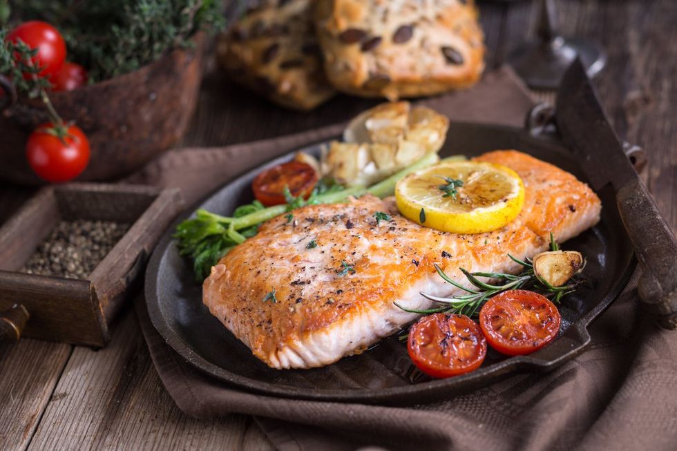 Filet of salmon with cooked vegetables on a cast iron skillet