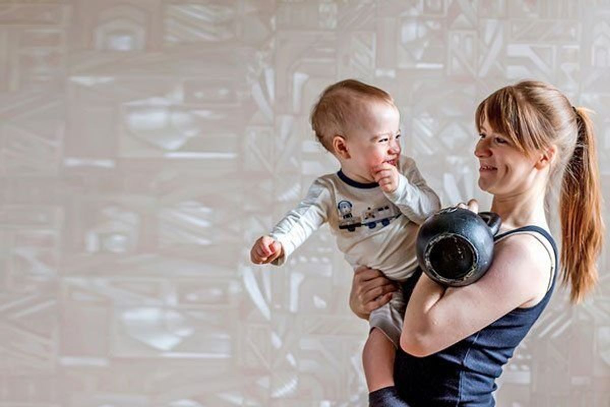 fit mom holding her child and a kettlebell