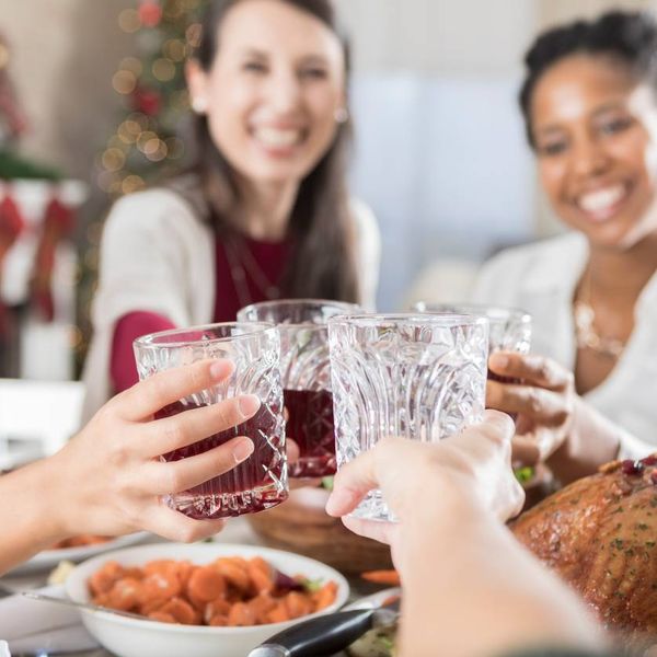 four drinking glasses as they are clinked above a full Christmas dinner table