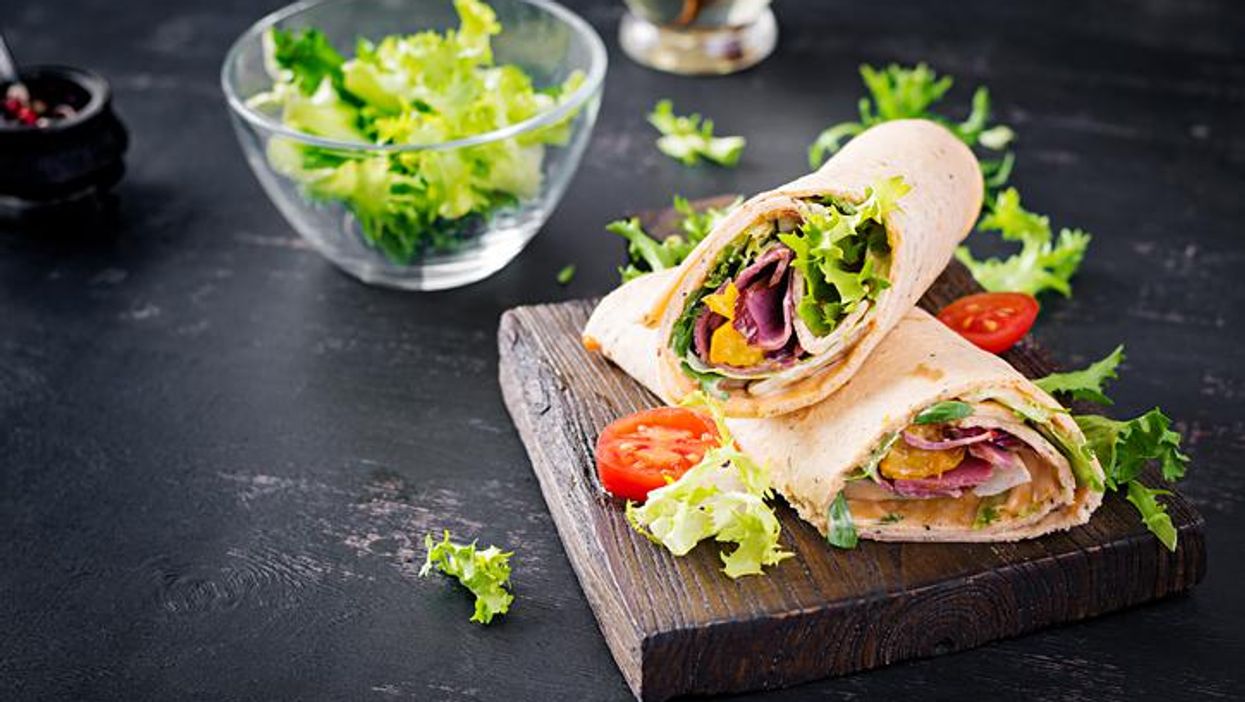 Fresh tortilla wraps with ham beef and fresh vegetables on wooden board