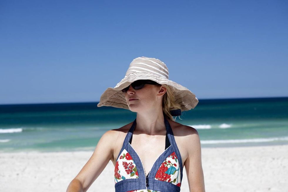 girl on the beach wearing a wide brim hat