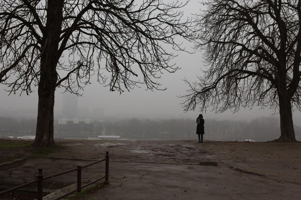 Girl standing alone in the park on gloomy day.