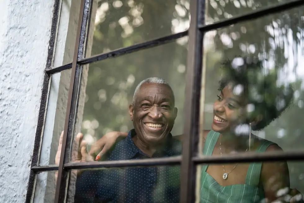 grandfather and granddaughter embracing through the window