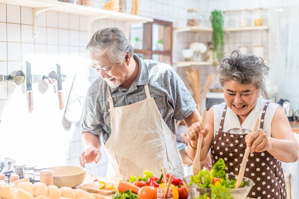 Grandfather cooking salad dish with grandmother with happiness and smile enjoy retirement life together