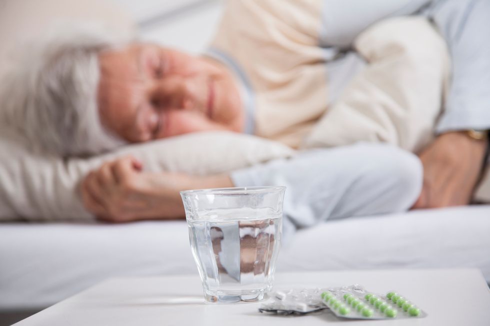 Grandmother sleeping in the bed with different pills on her night stand