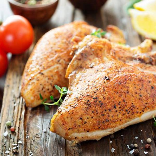 Grilled or smoked chicken breast with bone and skin on a cutting board