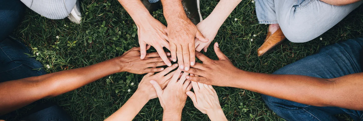 group of hands in the middle of a cirlce on the grass