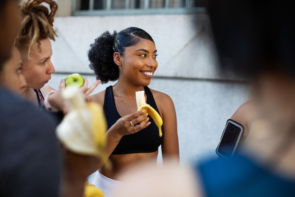 Group of women eating banana in workout training break