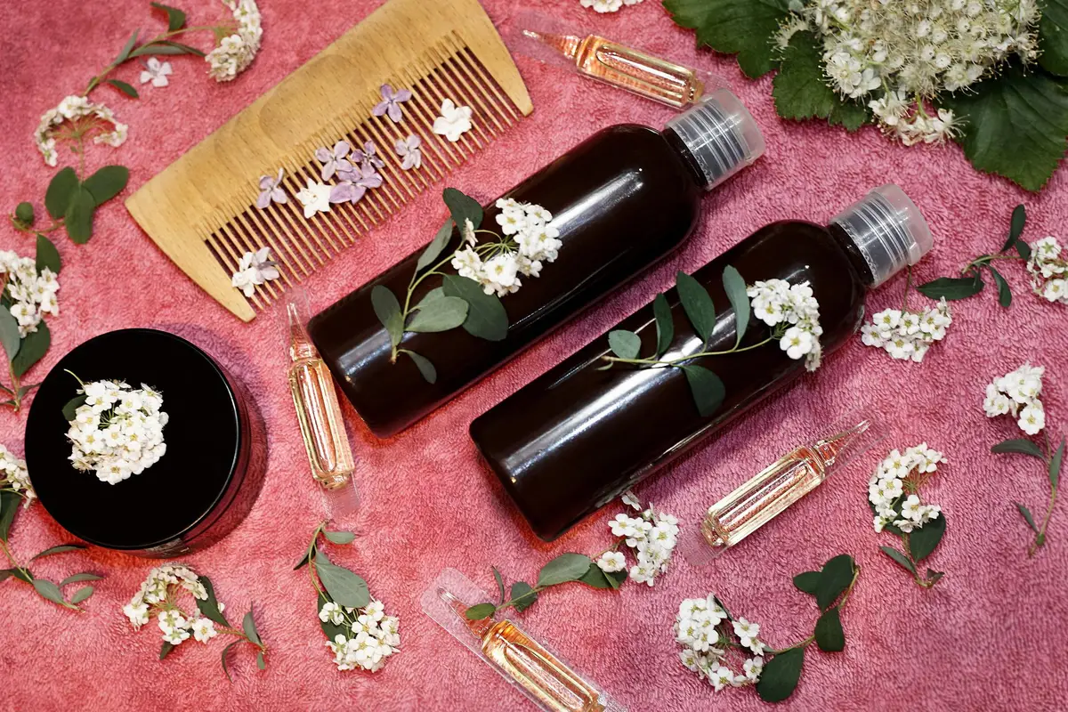 hair care product in fresh flowers on a pink towel.